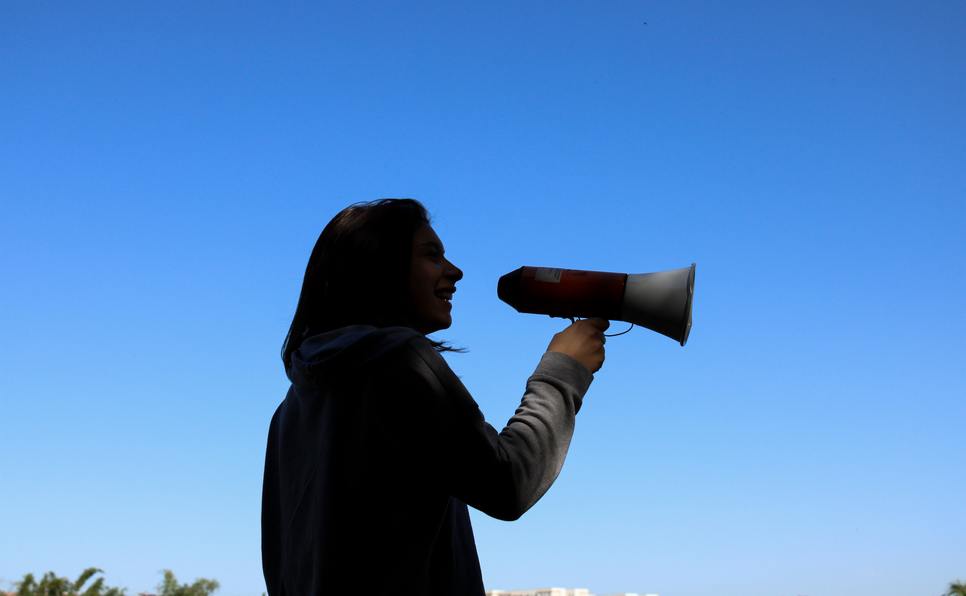 Woman holding a megaphone against a blue sky