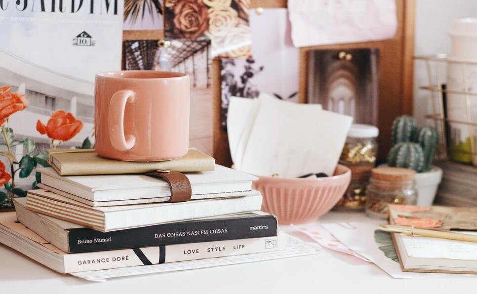 A pink mug, books, and flowers to represent the best boutique literary agencies