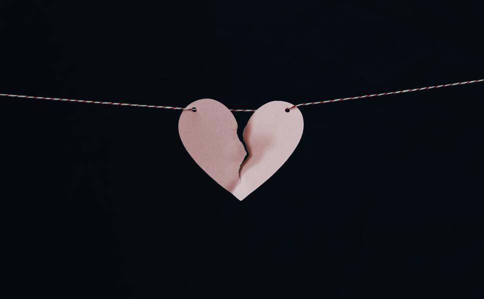 A pink broken paper heart on a black background representing how to break up with your literary agent
