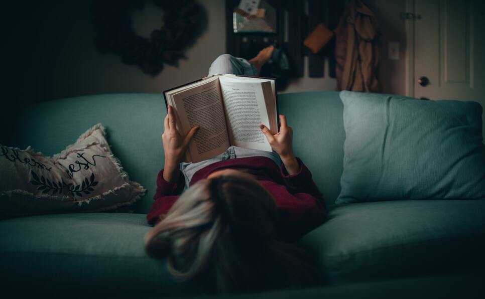 A woman on a couch reading literary fiction books